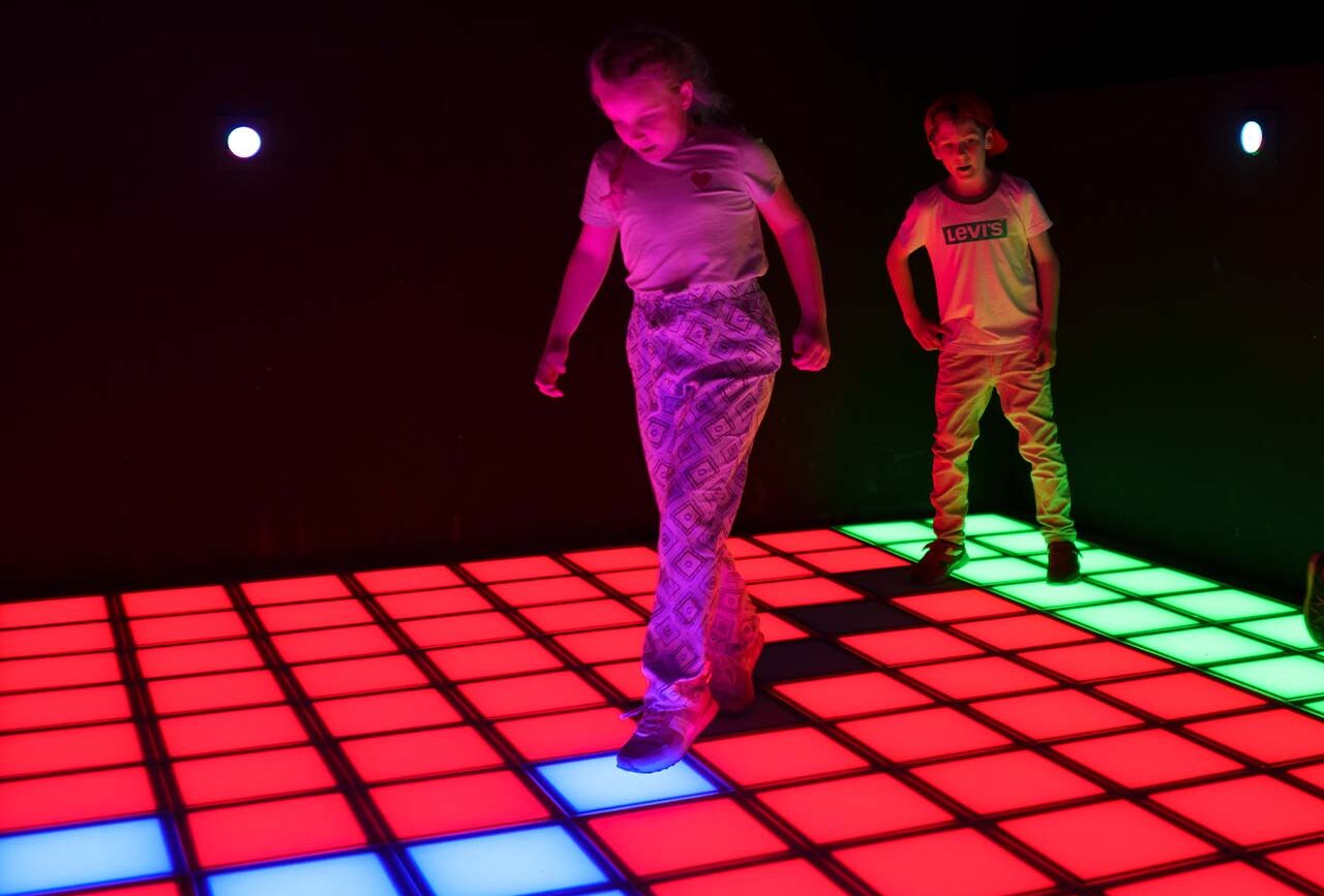 LED pixel game arena with players competing on interactive floor